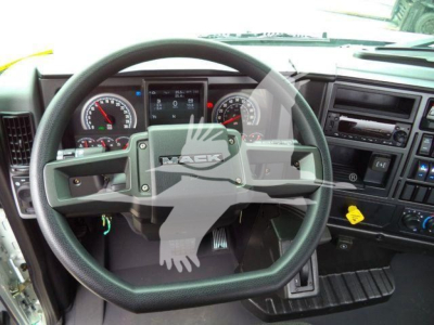 Mack MD6 truck dashboard steering wheel and instrument cluster view from cab. Visible are gauges, steering wheel with Mack logo, central display, and control panels.