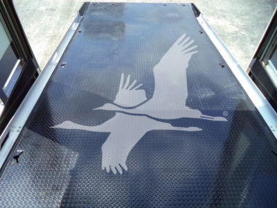 Mack MD6 rollback truck bed with a large white bird graphic on the diamond plate surface, viewed from inside the bed.