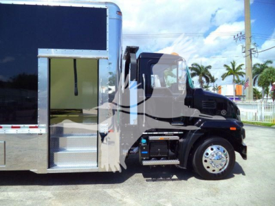 MD6 front/side view showing a Mack MD6 rollback truck with a large black cab, chrome wheel, and a metal utility area; no legible sticker text visible in the image.