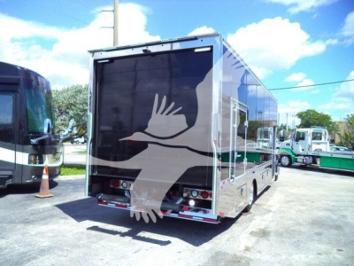 Mack MD6 rollback truck trailer showing rear view with reflective aluminum sides and rear lights.