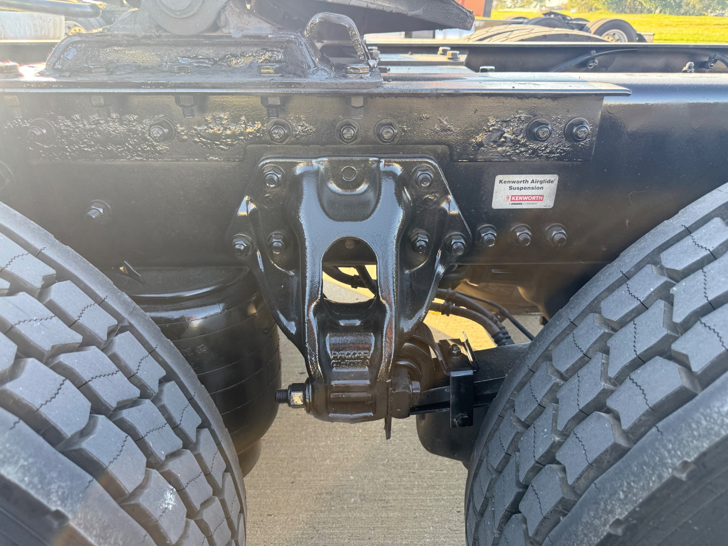 Kenworth T680 chassis showing articulation hitch and front suspension components with dual tires; VIN/stock tags and manufacturer label visible.