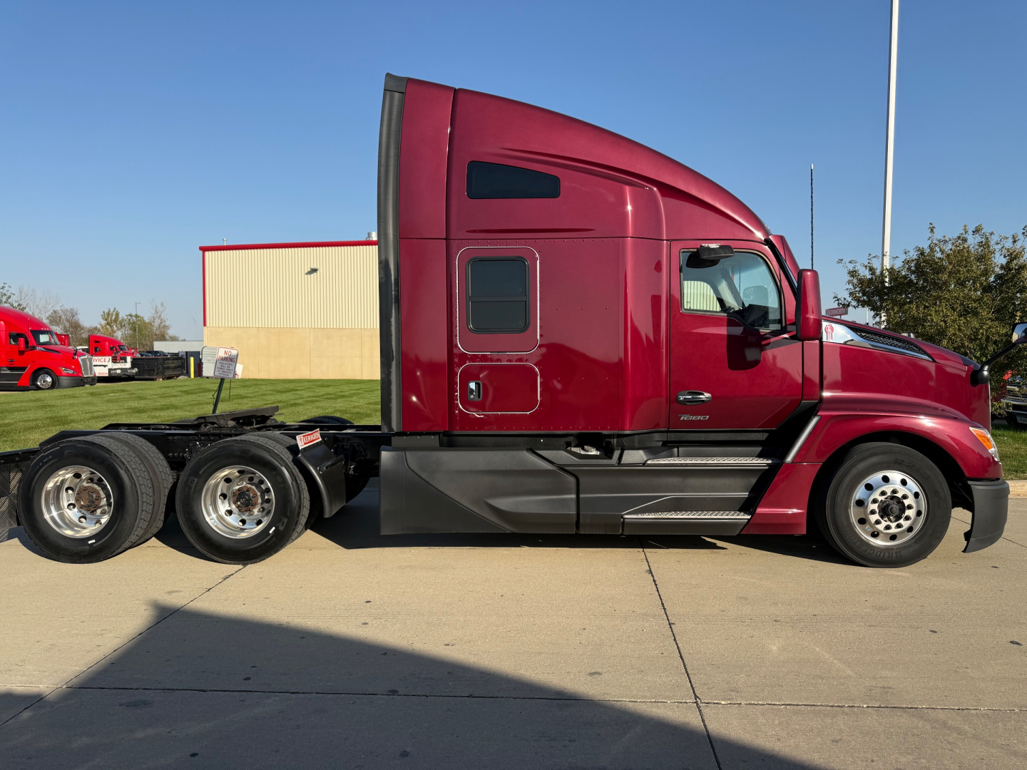 Kenworth T680 conventional sleeper truck side view showing cab and rear wheels with burgundy paint.