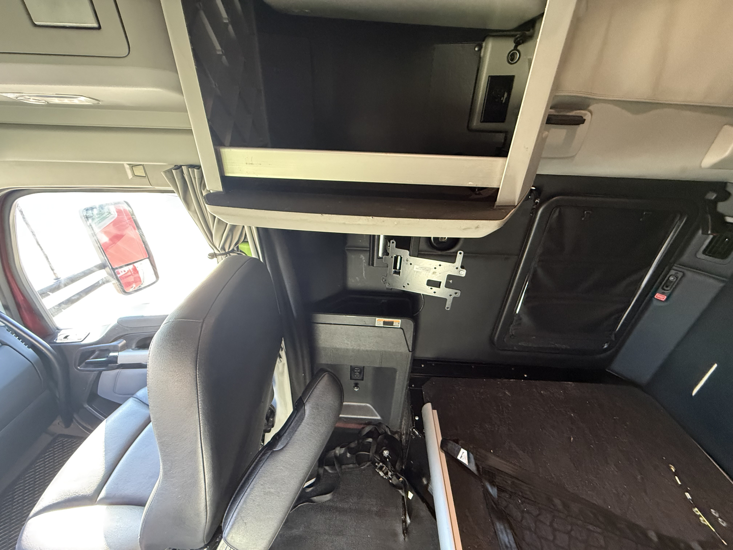 Cab interior of a 2023 Kenworth T680 showing a bunk area, overhead storage, and driver seat with controls visible.