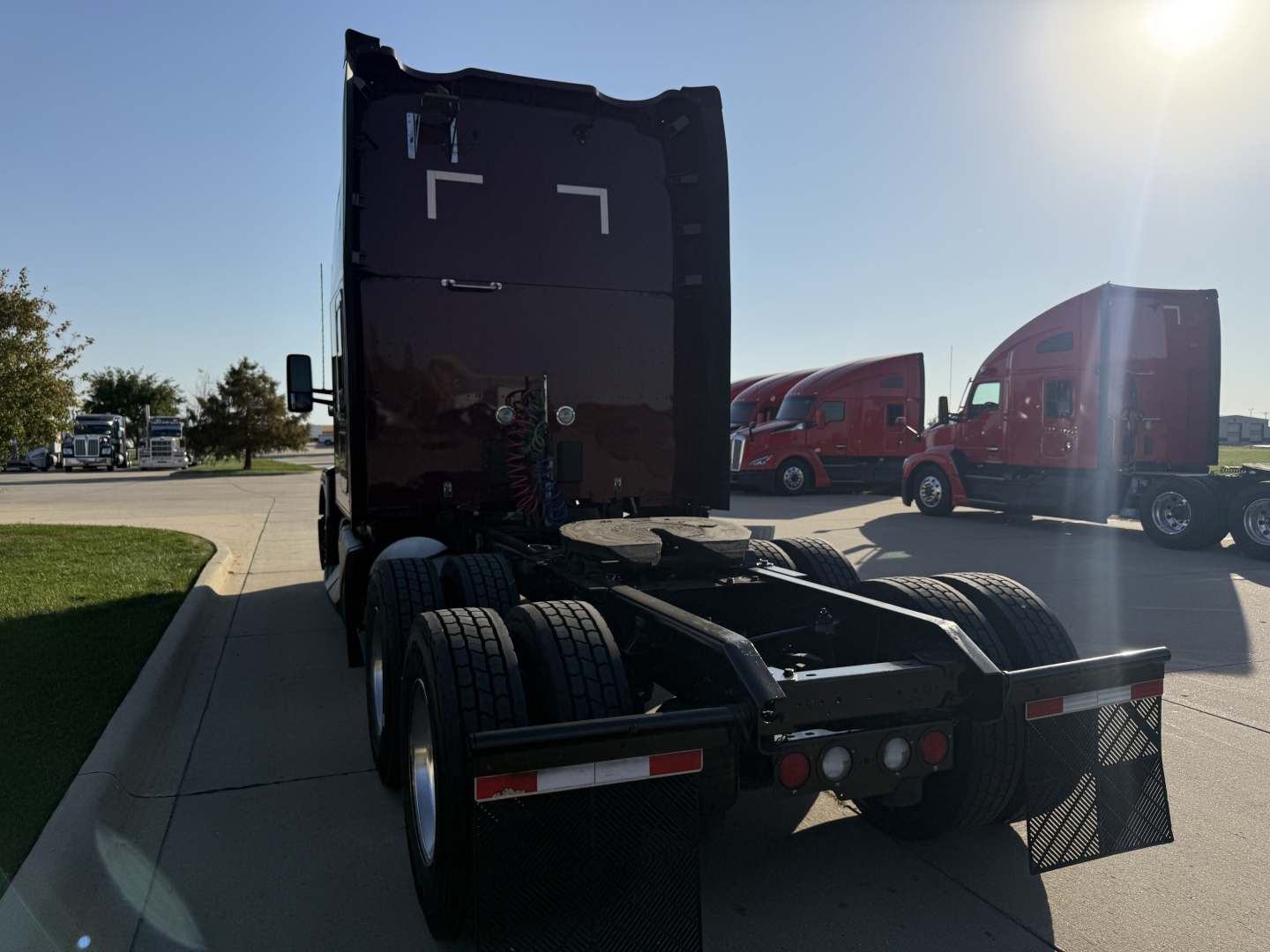 Kenworth T680 tractor rear view showing fifth wheel and dual rear axles, with visibility of mud flaps and rear lights.