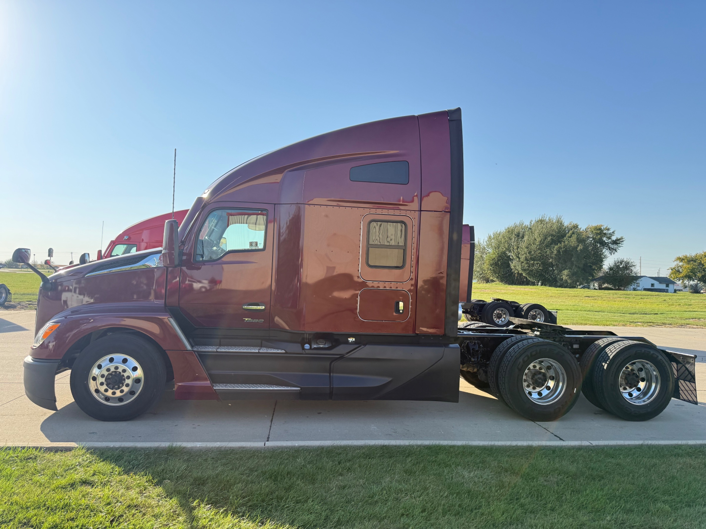 Kenworth T680 truck side view showing maroon cab and chassis with dual rear axles; side door and window visible; no visible text on the truck itself.