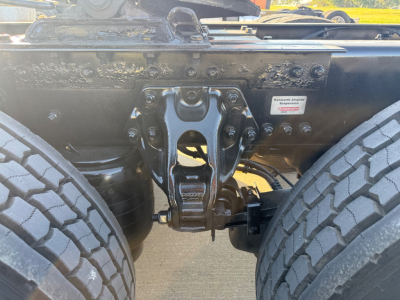 Kenworth T680 chassis showing articulation hitch and front suspension components with dual tires; VIN/stock tags and manufacturer label visible.