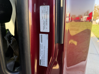 Kenworth T680 door jamb with VIN and compliance labels visible on maroon body panel.