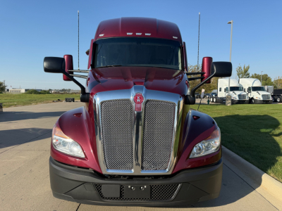 Kenworth T680 front view showing chrome grille, red cab, black bumper, and side mirrors.