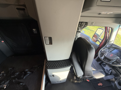 Kenworth T680 cab interior showing driver seat and overhead console with a vertical cabinet and storage area.