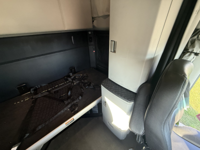 Truck cab interior showing sleeper area and side storage with seat and console.