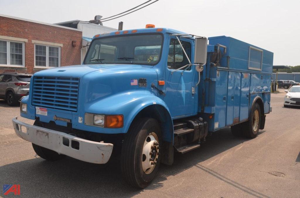 International 4700 utility truck with crane mounted in blue, front grille, and side compartments visible