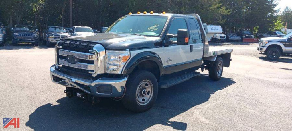 Ford F-350 Super Duty dual rear wheel pickup in a parking lot, chrome front bumper, white cab, black fender flares, dual rear wheel rear bed.