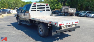 Flatbed tow truck rear/mid- rear view with aluminum flatbed and black bumper, Ford F-350 Super Duty chassis, VIN plate and taillights visible.