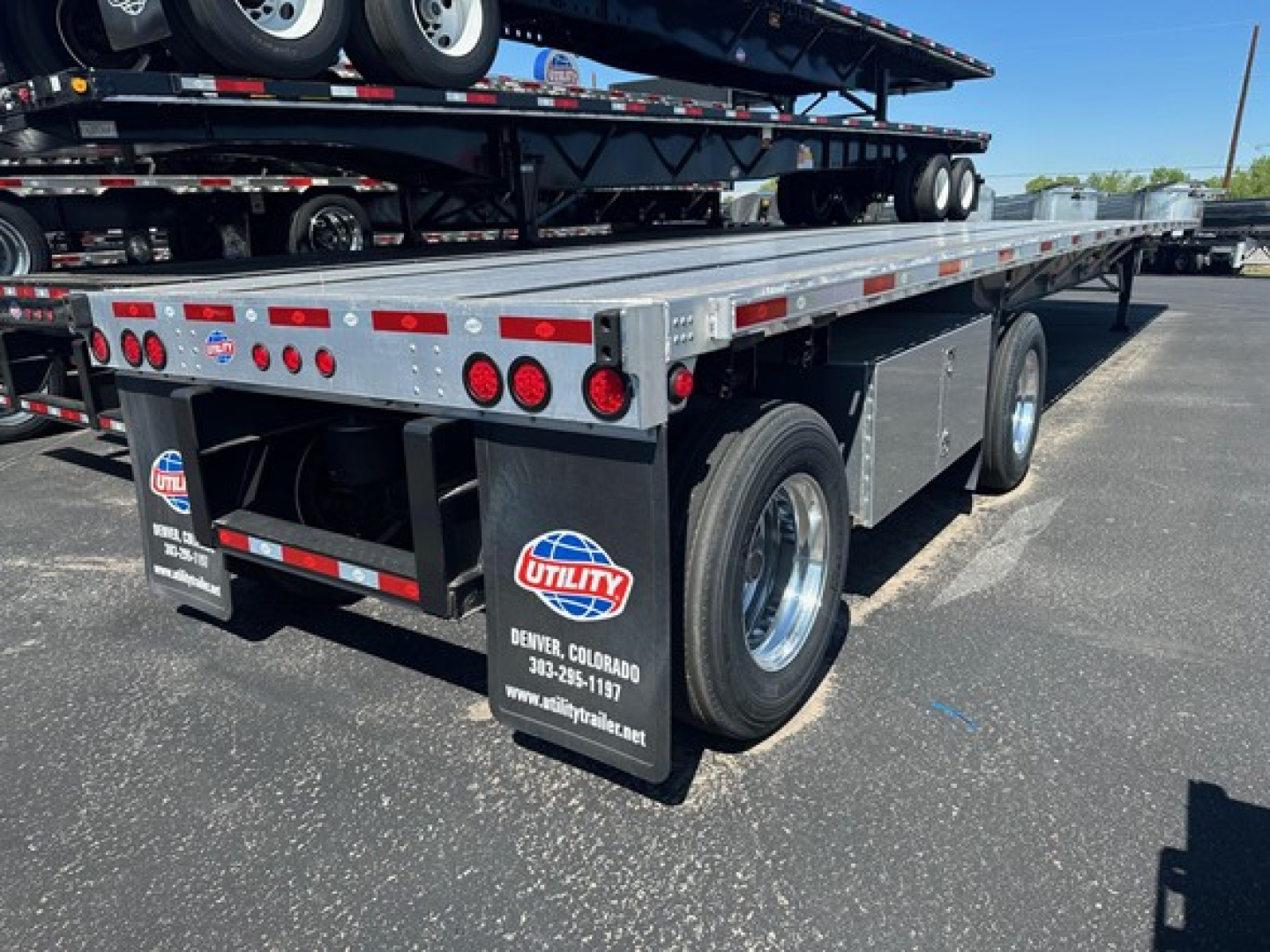 Trailer rear/side view showing Utility Spread Air Combo Flatbed with dual rear wheels, multiple taillights, and Utility branding on mud flaps.