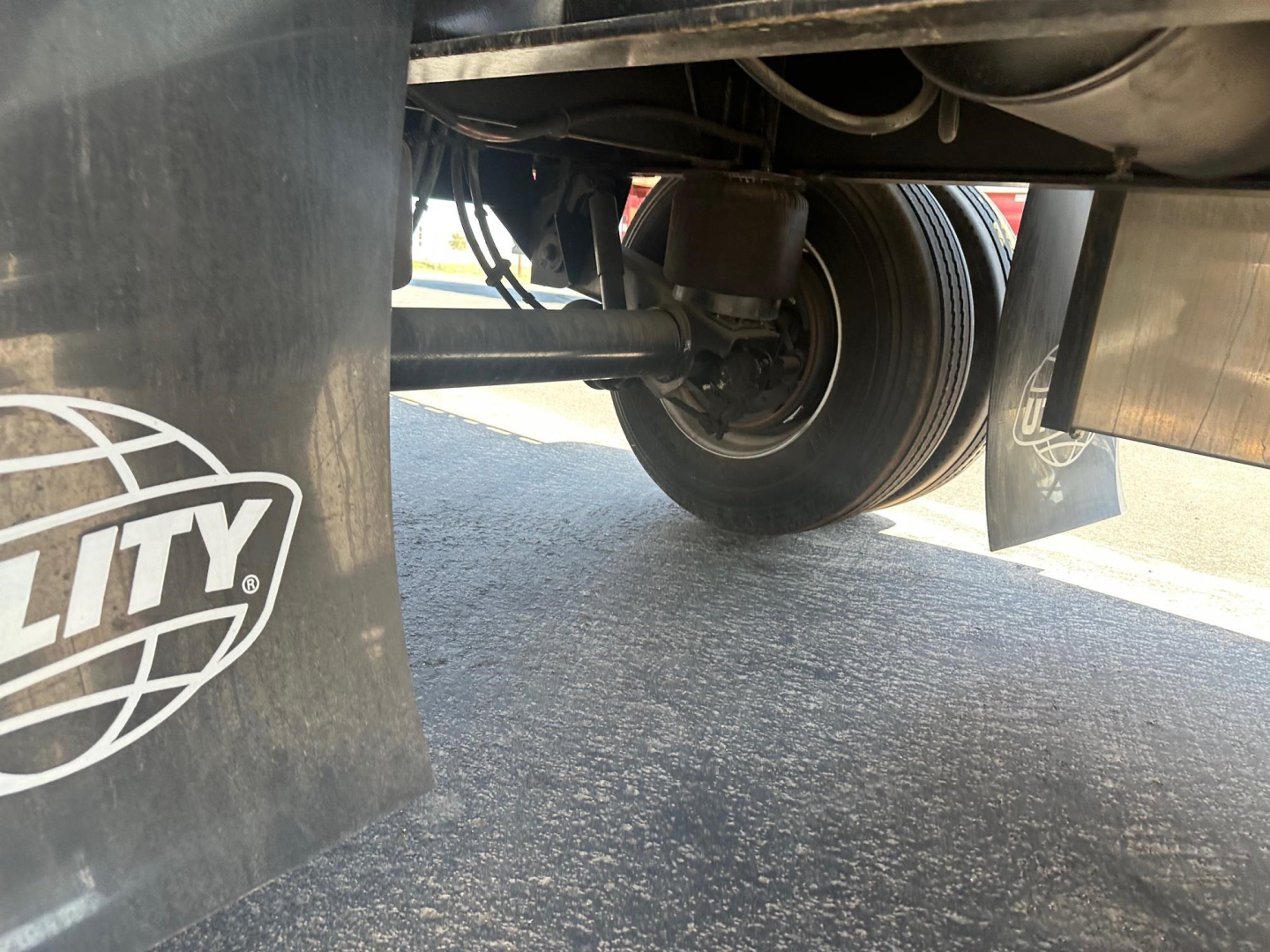 Trailer undercarriage showing wheel, suspension, and mudflap with Utility logo.