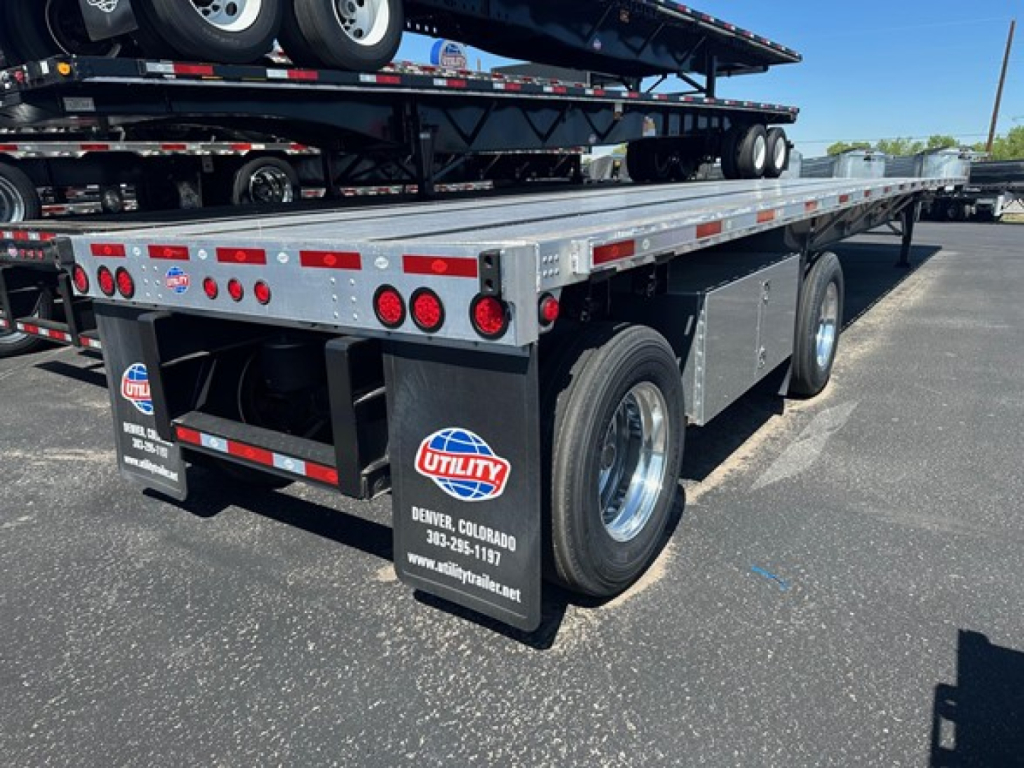 Trailer rear/side view showing Utility Spread Air Combo Flatbed with dual rear wheels, multiple taillights, and Utility branding on mud flaps.