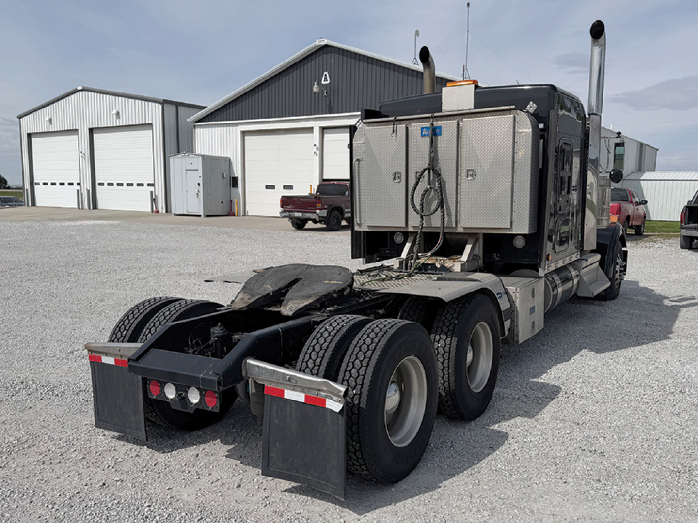 Kenworth W-900L AeroCab tractor rear view showing dual rear axles, fifth-wheel area, and exhaust stacks.