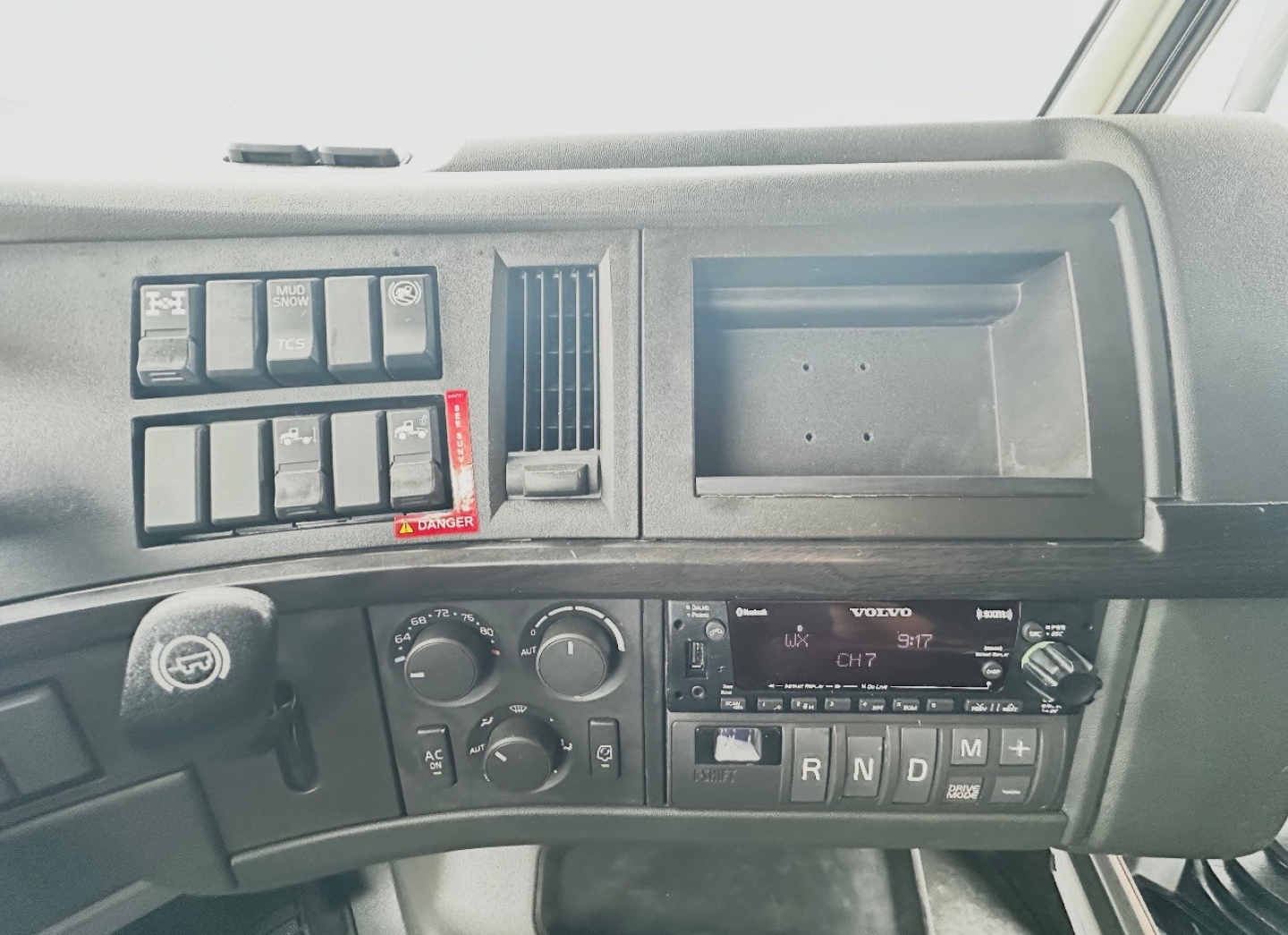 Volvo VNL860 dashboard view showing control switches, air vents, gear selector panel, and radio display.