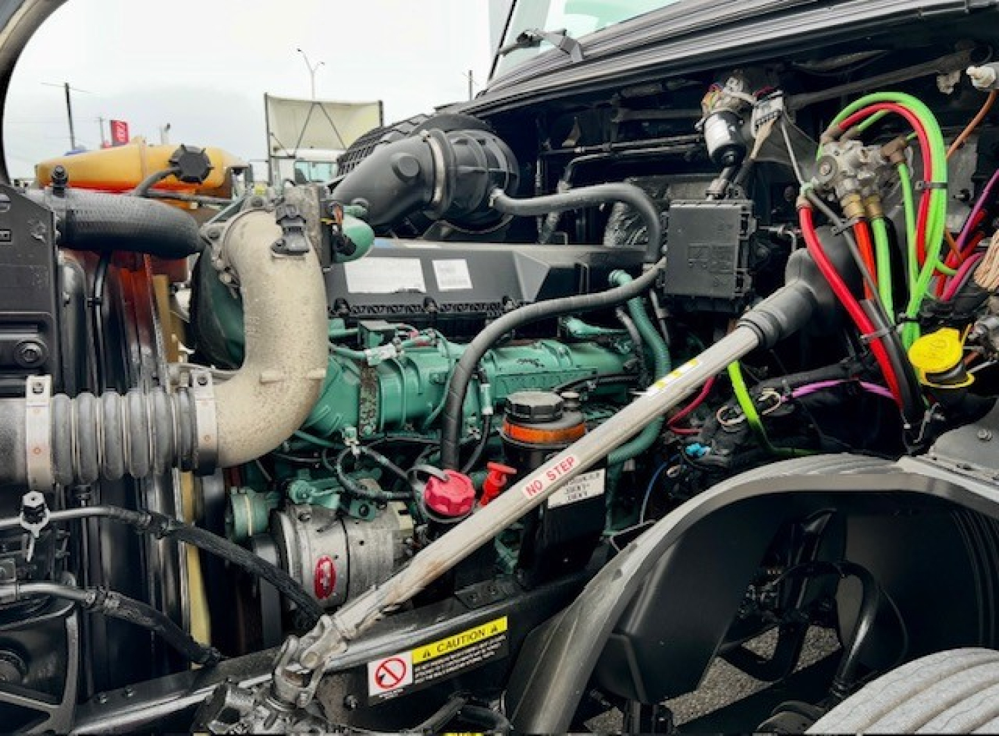  Volvo VNL860 engine bay showing diesel engine with green engine block, hoses, colored wiring, and radiator components.