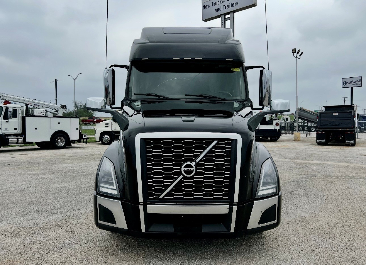 Volvo VNL860 truck front view showing bold grille and large bumper, in a dealership lot.