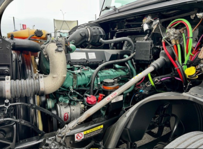  Volvo VNL860 engine bay showing diesel engine with green engine block, hoses, colored wiring, and radiator components.
