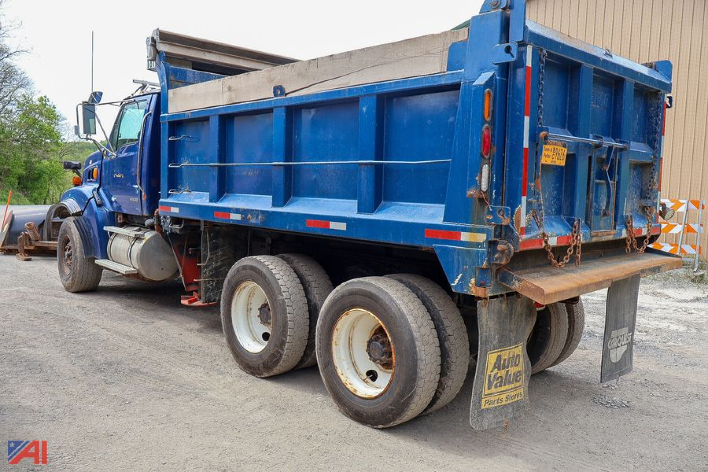 Dump truck rear and side view showing blue Sterling LT9500 dump bed with three axle wheels and rear tailgate.