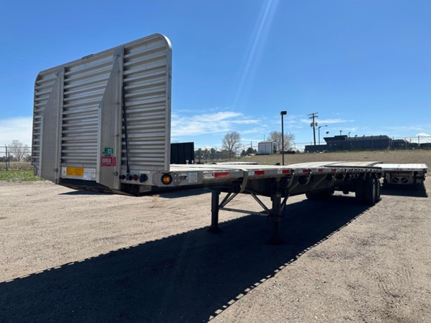Utility 4000Ae flatbed trailer in-service showing ramps folded at rear and dual-axle deck with support legs.