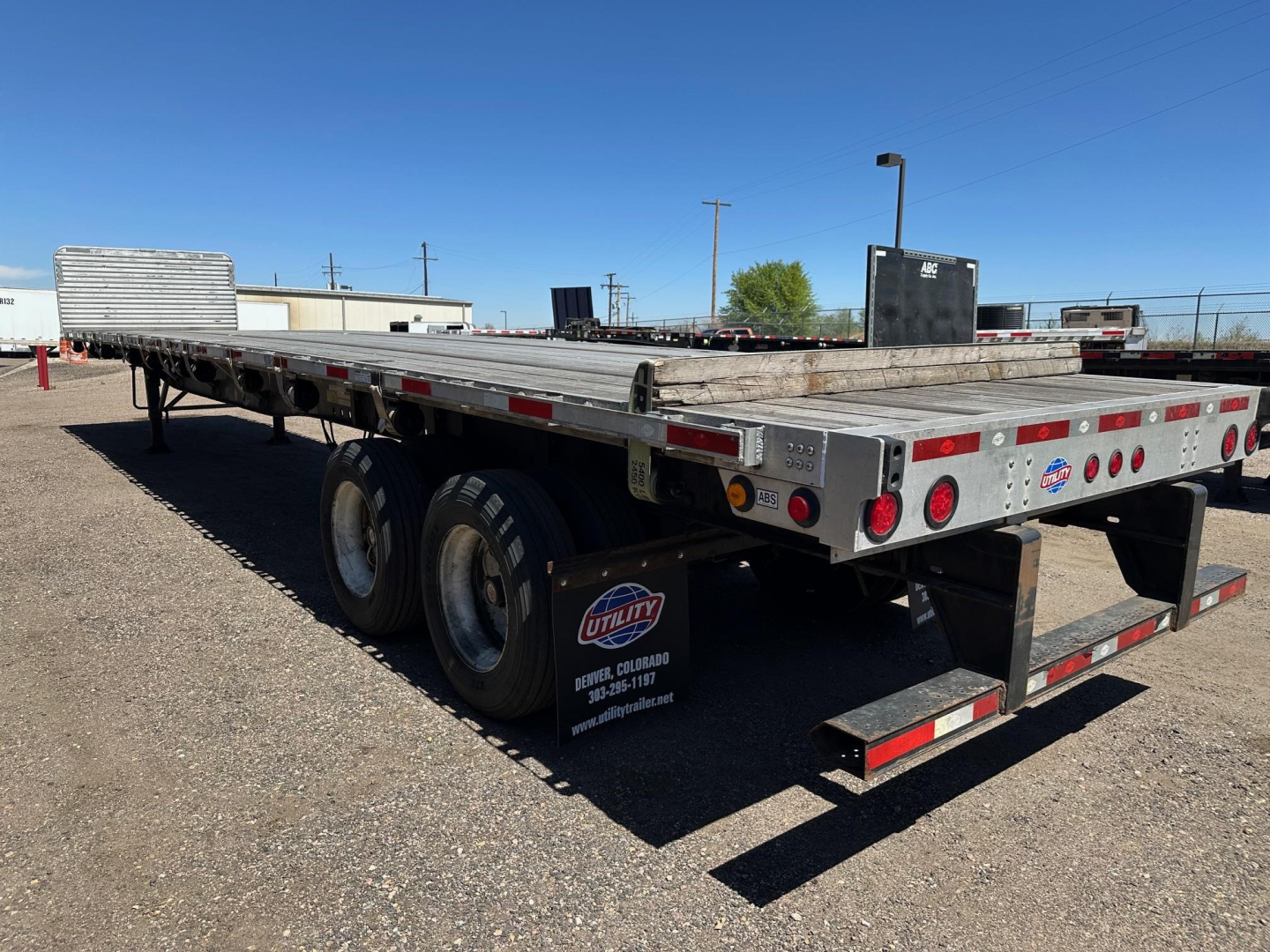 Utility 4000AE flatbed trailer showing dual rear axles, reflective tape, and rear lighting. Visible decals: Utility brand plate, safety cones, and small sticker details on the rear panels.