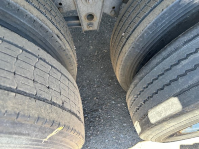 Trailer wheels close-up showing dual tires with tread and sidewall details, part of a used flatbed trailer undercarriage.