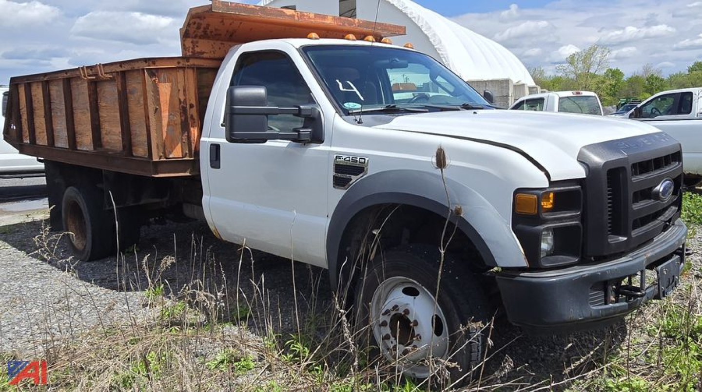 Ford F-450 XL Super Duty dump truck with white cab and orange dump bed, front view showing side, right wheel, and grille area.
