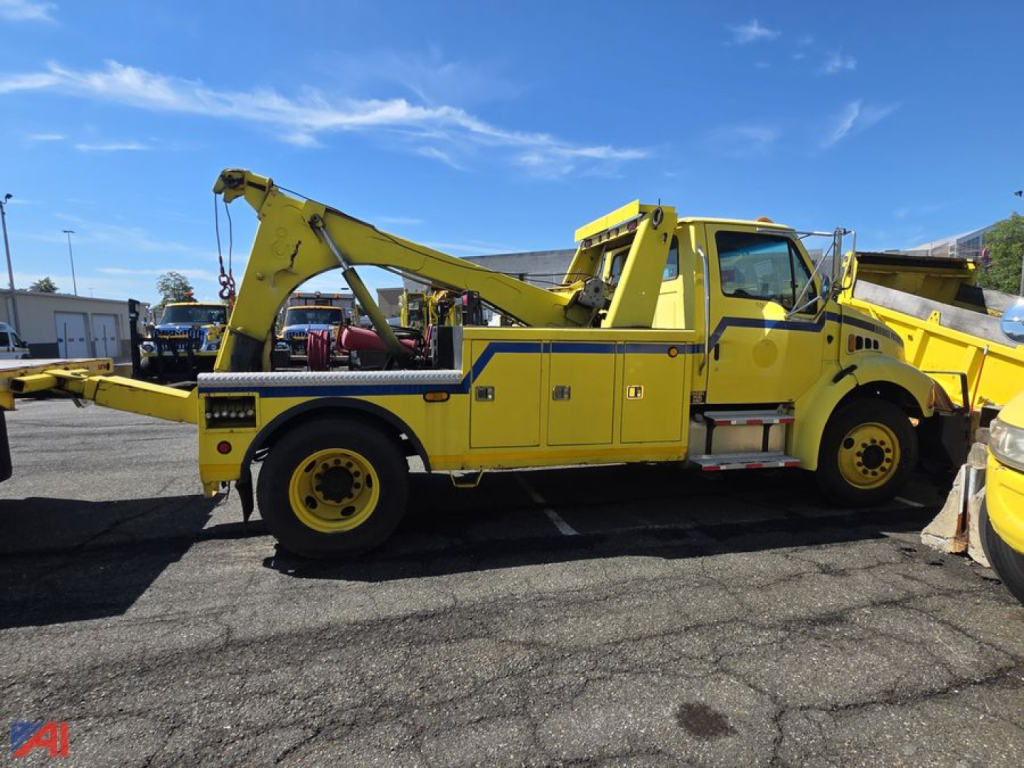 Tow truck with yellow wrecker body in side profile showing hydraulic boom and towing equipment.