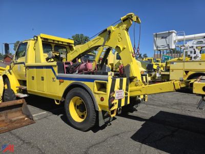 Tow truck with a yellow recovery wrecker arm, Sterling Acterra style, side view showing hydraulic boom and rear wheel, used tow truck in a yard