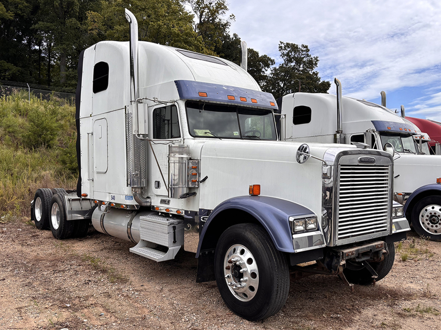 Semi truck cab and front chassis of a Freightliner with chrome grille and sleeper cab, parked outdoors.