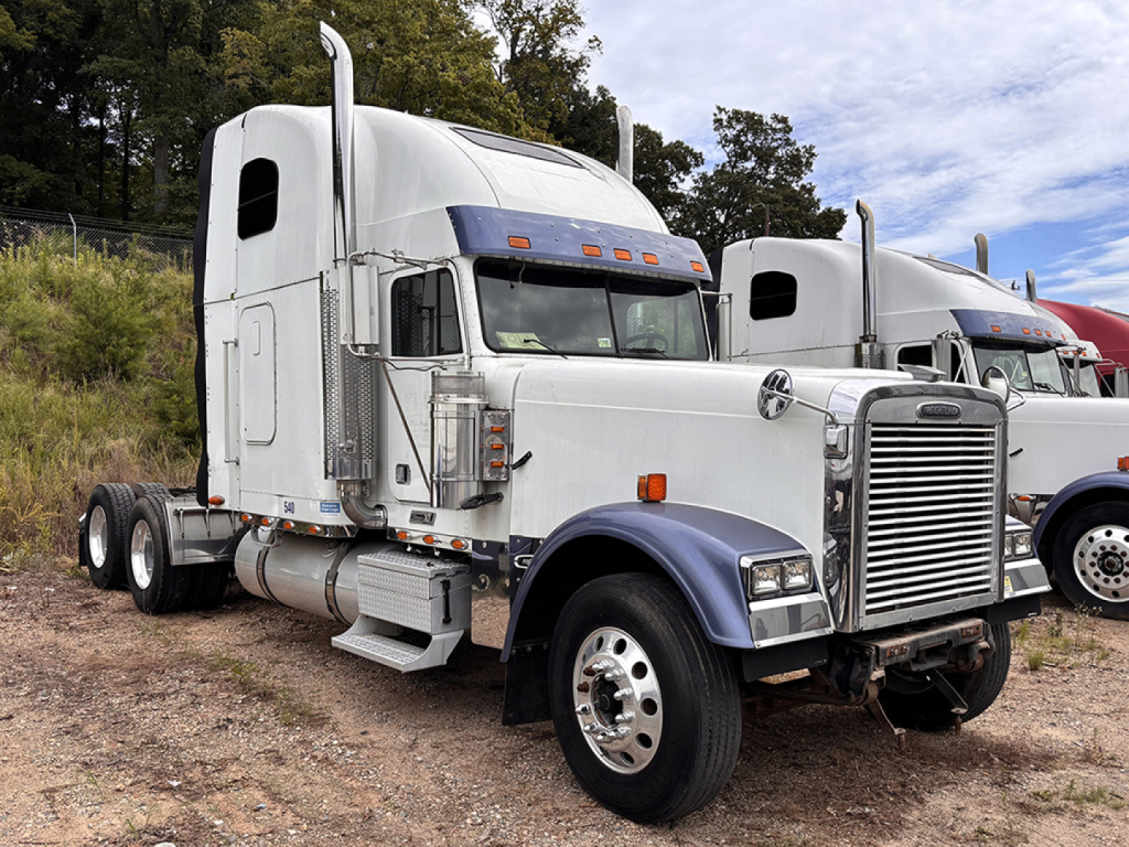 Semi truck cab and front chassis of a Freightliner with chrome grille and sleeper cab, parked outdoors.