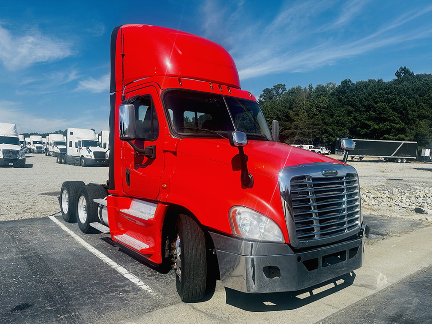 Freightliner Cascadia125 cab with red exterior, front grille, and dual rear axles in a lot.