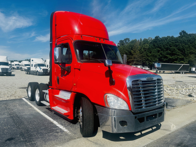 Freightliner Cascadia125 cab with red exterior, front grille, and dual rear axles in a lot.