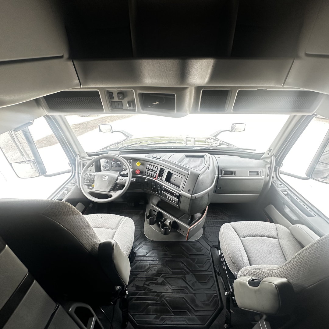 Volvo VNL860 truck cab interior showing steering wheel and dashboard with controls and seating area.