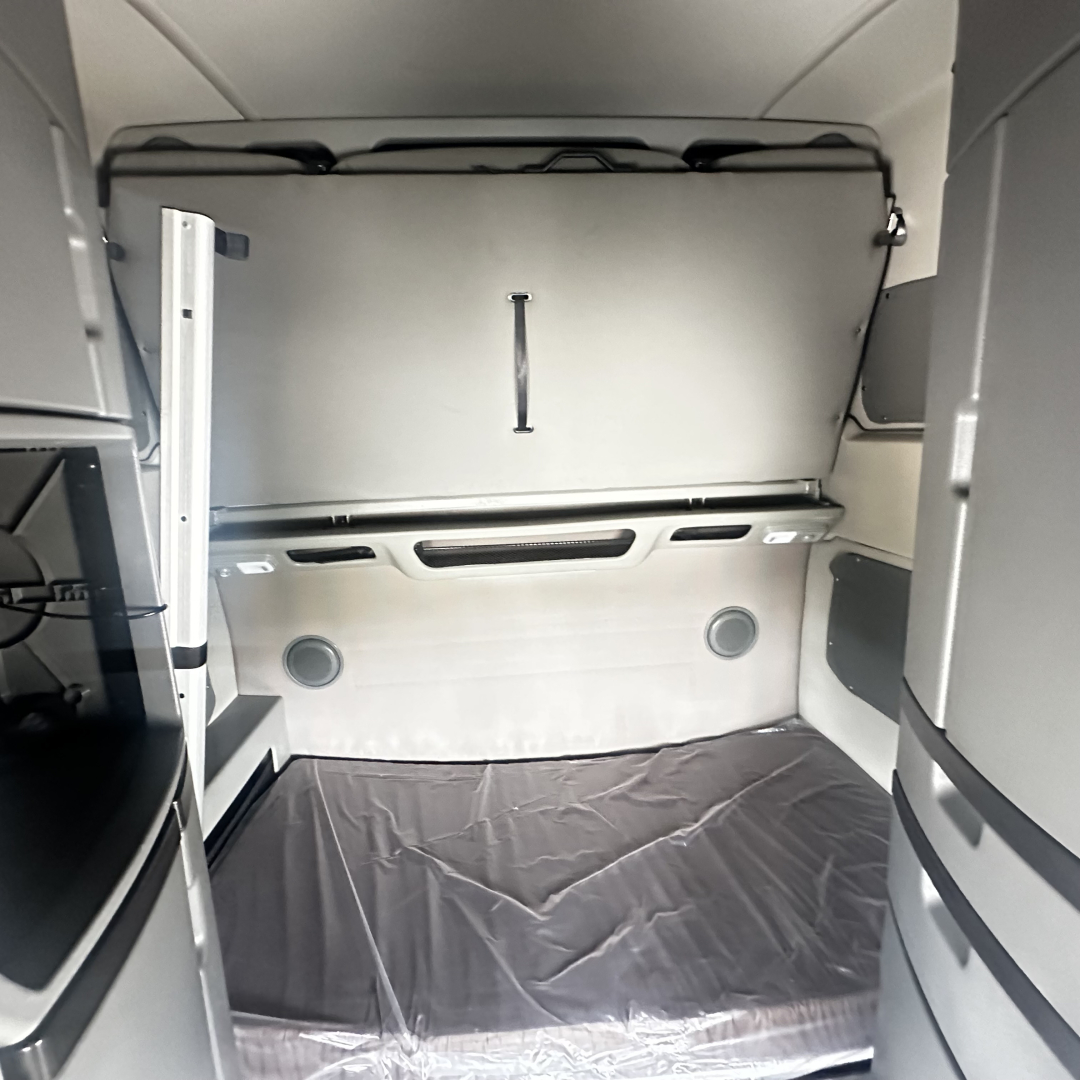 Volvo VNL860 sleeper cab interior showing cargo area and rear wall with overhead storage hatch.