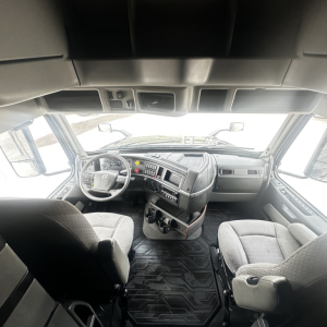 Volvo VNL860 truck cab interior showing steering wheel and dashboard with controls and seating area.