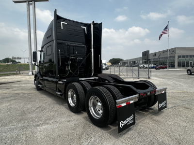 Volvo VNL860 sleeper cab tractor showing rear view with fifth wheel and dual rear axles, black paint, chrome wheels, and Bruckner mudflaps.