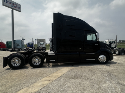 Volvo VNL860 tractor in profile view showing sleeper cab and triple rear axles.