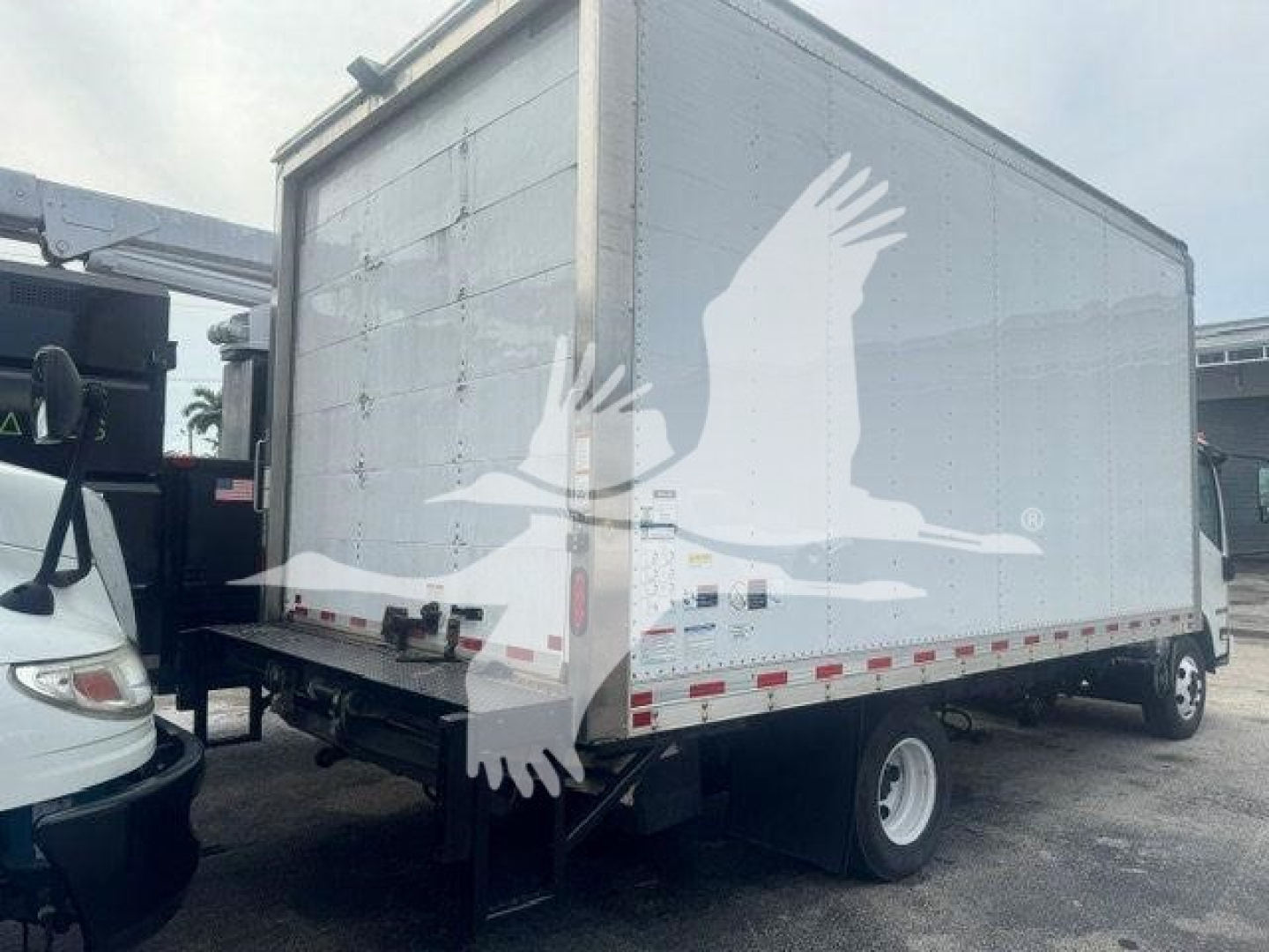 Isuzu NPR-HD box truck rear/side view showing plain box body with no visible text, and rear undercarriage with a utility hitch.
