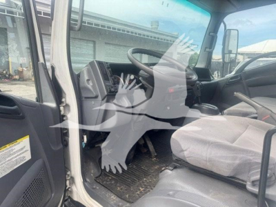 Isuzu NPR HD truck cab interior view showing driver's seat, steering wheel, dashboard, and entry area.