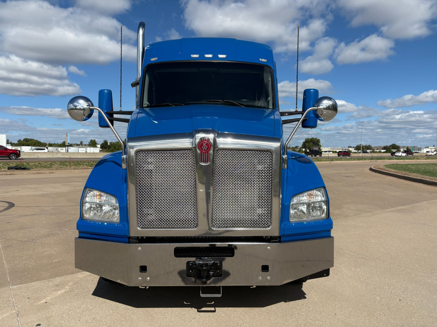 Blue 2020 Kenworth T880 front view showing large chrome grille, round mirrors, bumper, and emblem.