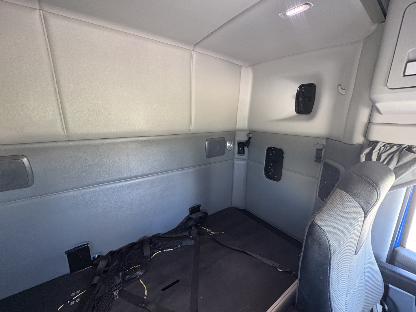 Kenworth T880 sleeper cab interior showing side wall panels and seat with seatbelt anchors.