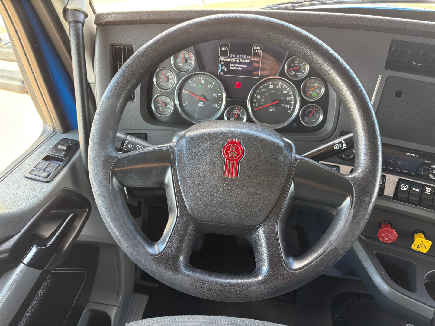 Kenworth T880 truck interior showing steering wheel with red emblem and instrument cluster
