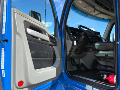 Kenworth T880 truck cab interior visible through open door showing steering wheel, driver seat, and dashboard from door jamb view.