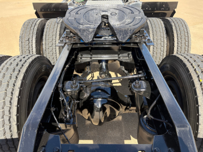 Kenworth T880 chassis drivetrain rear view showing dual rear axles and fifth wheel, undercarriage components and suspension visible.