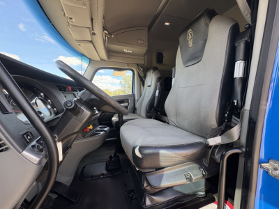 Cab interior of a 2020 Kenworth T880 showing driver's seat and steering wheel with grey upholstery and a glimpse of the dashboard
