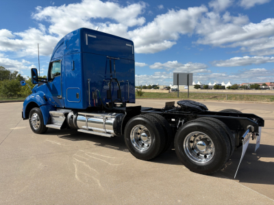 Kenworth T880 truck cab and dual rear axles side view showing blue sleeper tractor with chrome fuel tanks and wheels.